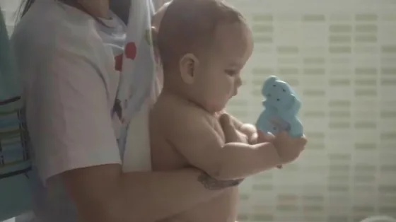 Bebê sentado segura um brinquedo azul