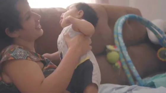 Mãe sorri para a bebê que segura no colo