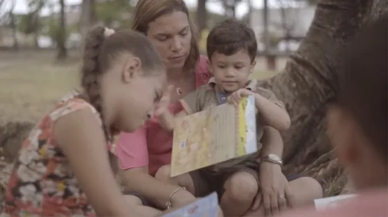 Mãe lê um livro com duas crianças