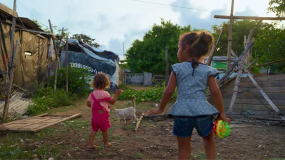 Duas crianças caminham por um terreno de comunidade