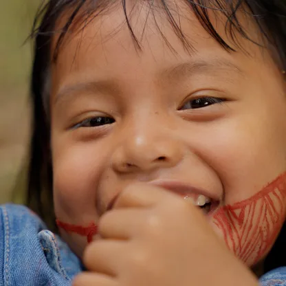 Menina indígena com pintura no rosto sorrindo